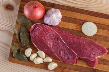 Et, defne yaprağı, sarımsak ve soğan bir kesme tahtası üzerinde