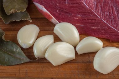 Et, defne yaprağı, sarımsak ve soğan bir kesme tahtası üzerinde