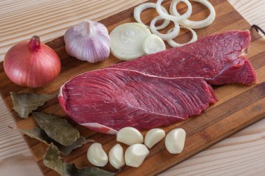Et, defne yaprağı, sarımsak ve soğan bir kesme tahtası üzerinde
