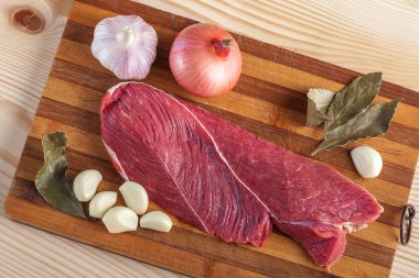 Et, defne yaprağı, sarımsak ve soğan bir kesme tahtası üzerinde