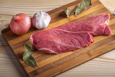 Et, defne yaprağı, sarımsak ve soğan bir kesme tahtası üzerinde