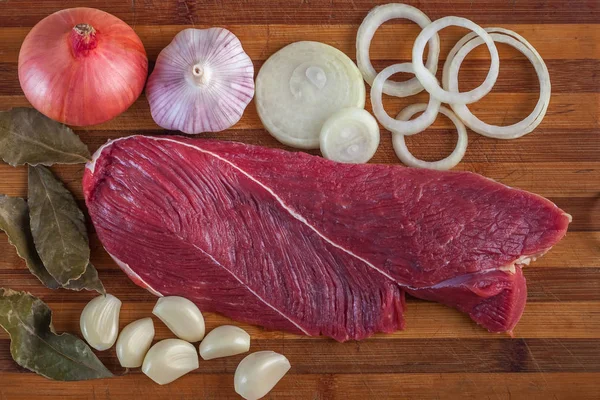 Et, defne yaprağı, sarımsak ve soğan bir kesme tahtası üzerinde