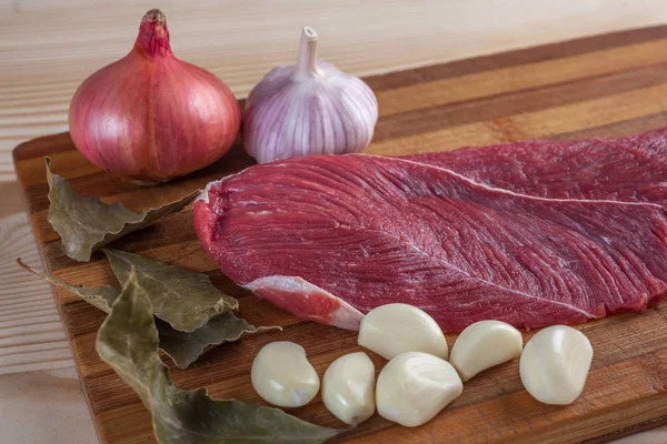 Carne, laurel, ajo y cebolla en una tabla de cortar —  Fotos de Stock