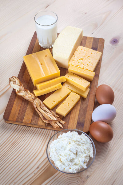 cheese and dairy products on a wooden board with eggs