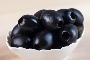 Beyaz ahşap masa üzerinde siyah zeytin ile kase