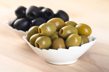 ahşap masa üzerinde yeşil ve Siyah Zeytin ile kase