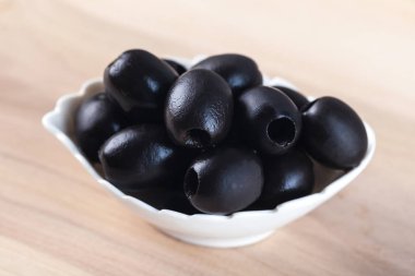 Beyaz ahşap masa üzerinde siyah zeytin ile kase