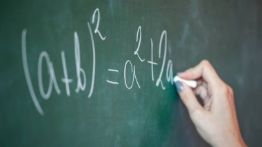 Kız onun elinde tebeşir ile üzerinde matematiksel bir sorunu çözer