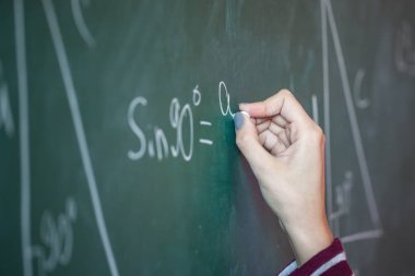 Kız onun elinde tebeşir ile üzerinde matematiksel bir sorunu çözer