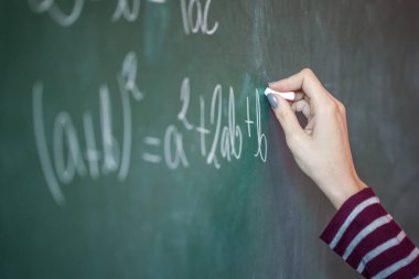 Kız onun elinde tebeşir ile üzerinde matematiksel bir sorunu çözer