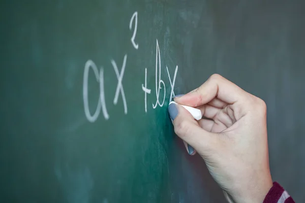 Girl with chalk in her hand solves a mathematical problem on the — Stock Photo, Image