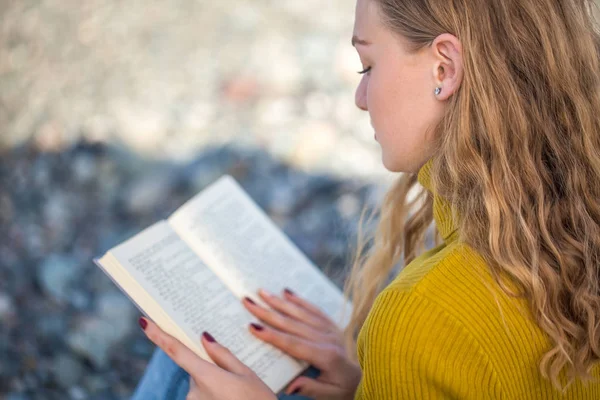 Hermosa chica rubia está leyendo un libro en la playa — Foto de Stock