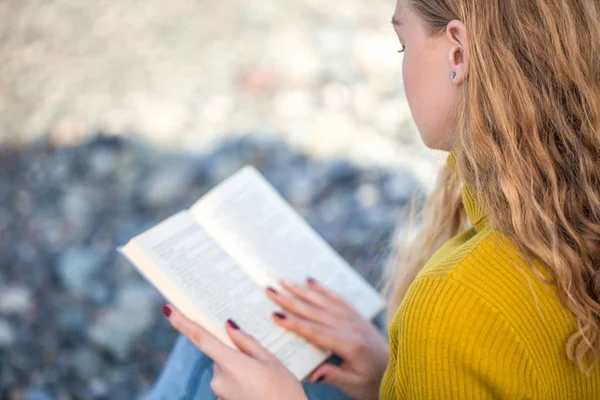 Linda menina loira está lendo um livro na praia — Fotografia de Stock