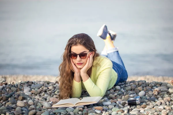 Vacker flicka en bok på stranden — Stockfoto