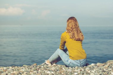 güzel sarışın kız sahilde oturan ve bakarak