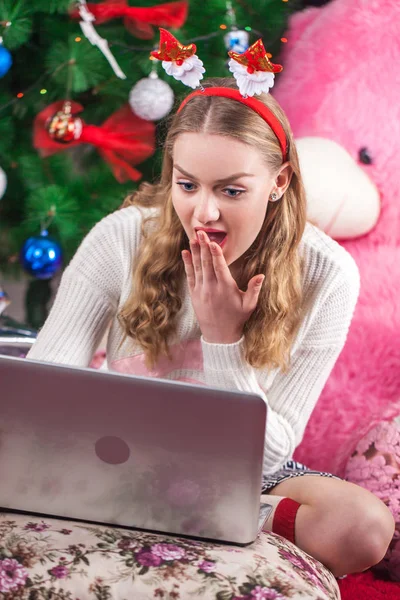 美丽的 blunde 女孩使用笔记本电脑坐在枕头上。冬天 — 图库照片