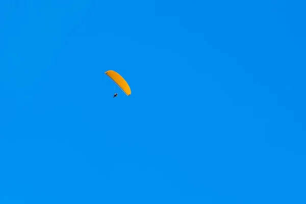 En paraglider som flyger i blå himmel på berg och dalar landskap — Stockfoto