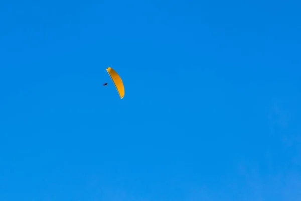 Un parapente volant dans le ciel bleu sur les montagnes et les vallées landsca — Photo