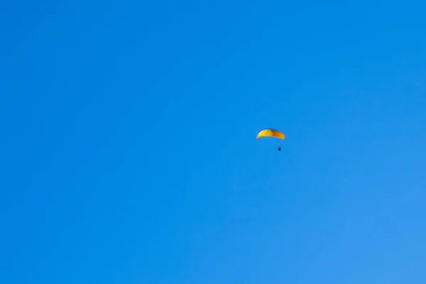 Параплан, летящий в голубом небе над горами и долинами ландшафта — стоковое фото