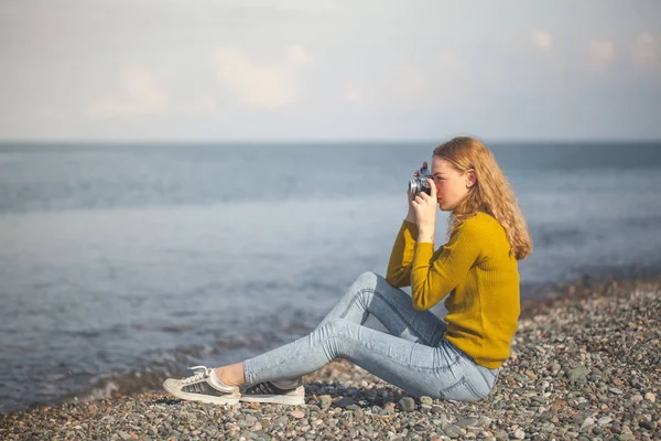 Belle fille blonde sur une plage de la mer avec une vieille caméra à la main — Photo