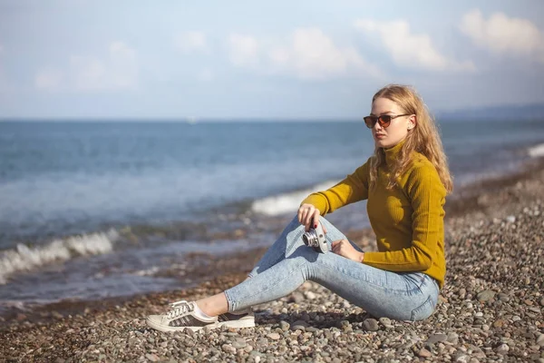 손에서 오래 된 카메라와 함께 바다 해변에 아름 다운 금발 소녀 — 스톡 사진