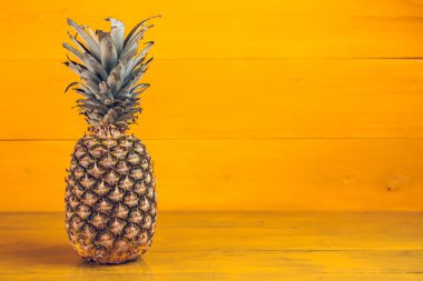 Sarı ahşap arka planda olgun ananas.