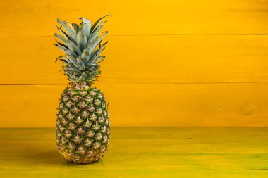 Sarı ahşap arka planda olgun ananas.