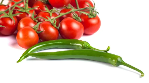 Tomates e pimentas verdes sobre um fundo branco . — Fotografia de Stock