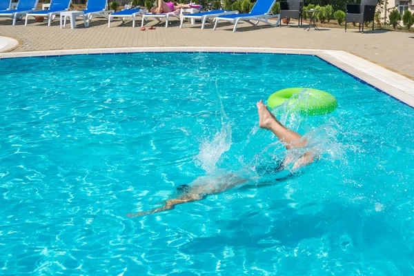 Hombre joven saltando en la piscina en el complejo — Foto de Stock