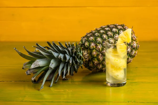 Стерти ананас і сік у склянці на жовтому дерев'яному фоні — стокове фото