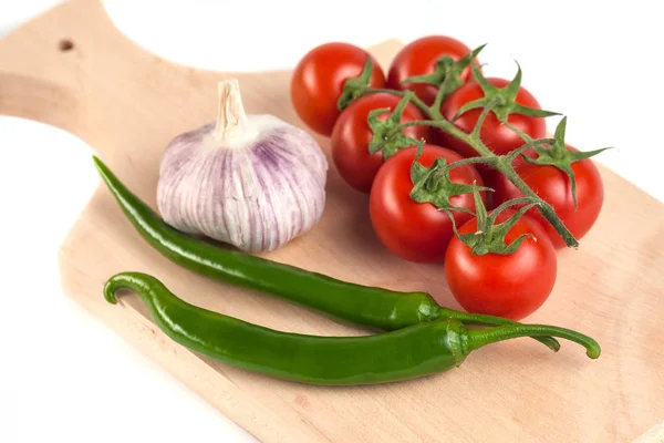 Tomates, ajo y pimientos verdes en la tabla de cortar de madera , — Foto de Stock