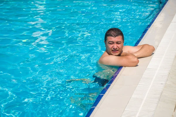 Porträtt av ung man koppla av i poolen, sommar utomhus — Stockfoto