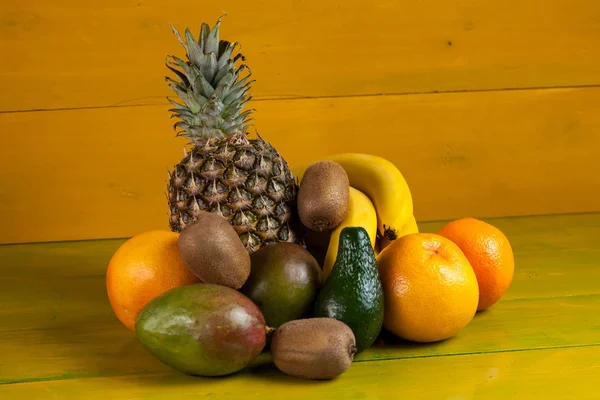 Tropical fruit on yellow wooden background, fresh food — Stock Photo, Image