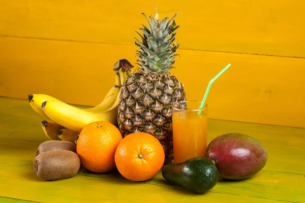 Тропічні фрукти на жовтому дерев'яному фоні, свіжа їжа — стокове фото