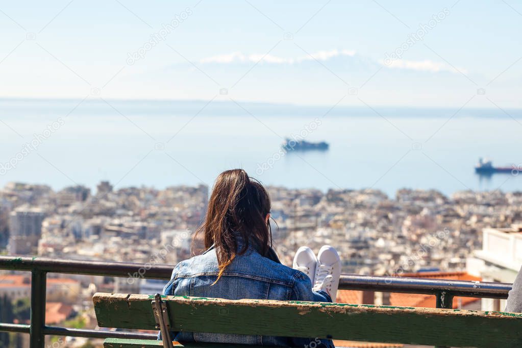 Girl sitting on a bench looking at the gulf in Thessaloniki, Gre