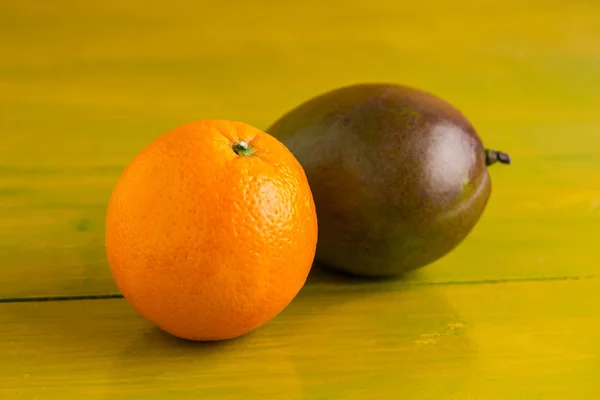 Apelsin och mango på gula träbord, färsk mat — Stockfoto