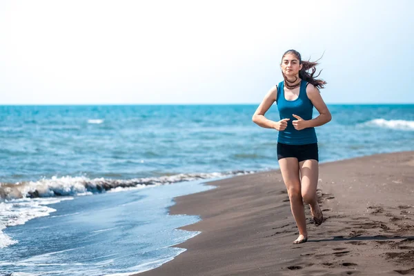 Hermosa chica deportiva corriendo a lo largo de hermosa playa de arena, hea — Foto de Stock