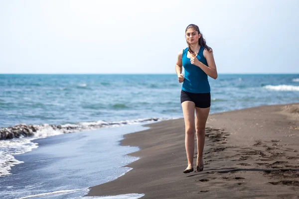 Hermosa chica deportiva corriendo a lo largo de hermosa playa de arena, hea — Foto de Stock