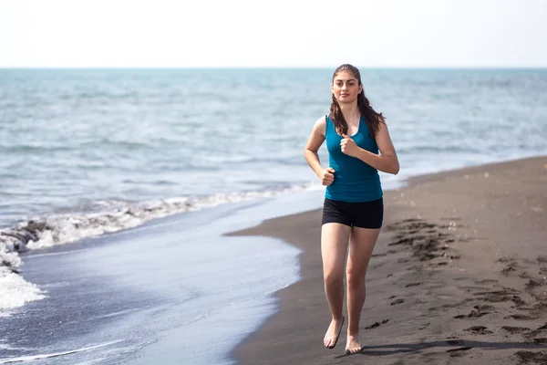 Hermosa chica deportiva corriendo a lo largo de hermosa playa de arena, hea — Foto de Stock
