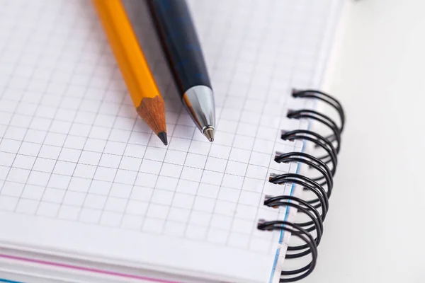 Blauwe ballpoint pen en potlood op de notebook — Stockfoto