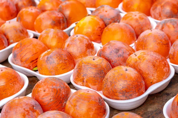 Reihen von frischem, reifem Kaki, der auf einem Wochenmarkt zum Verkauf steht — Stockfoto