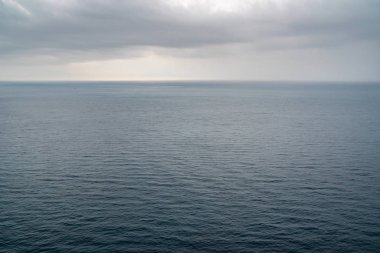 Bulutlu bir günde küçük dalgalarla mavi deniz yüzeyi.