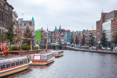 Amsterdam, Hollanda - 16.10.2019: Su üzerindeki tarihi apartman evleri ve kanal turlarına hazır tekneler