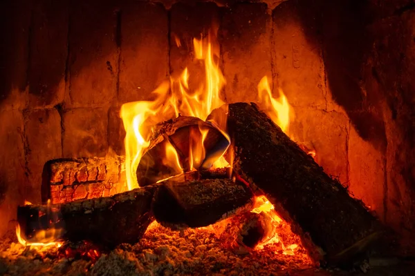 Fuego en una chimenea con troncos y llamas creando una sensación de calidez y calidez . — Foto de Stock