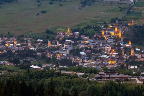 Evening view on Mestia with its illuminated Svan Towers. Svaneti, Georgia. — Stock Photo, Image