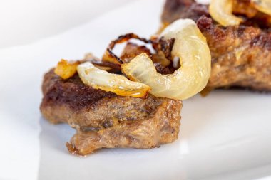 Beyaz tabakta soğanlı ve limonlu biftek..