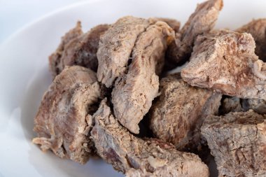 Beyaz bir arka planda izole edilmiş beyaz bir tabakta haşlanmış et.