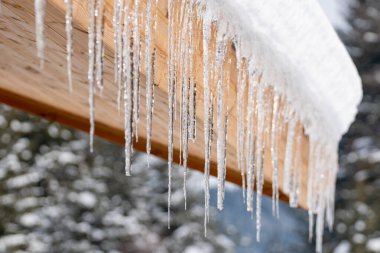 Icicles hang from the snowy roof of a mountain cottage
