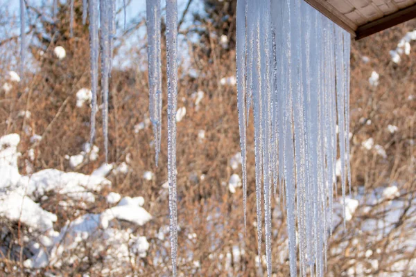 Icicles hang from the snowy roof of a mountain cottage — Stock fotografie