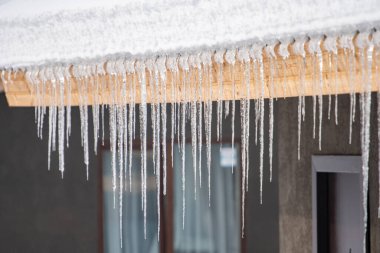 Icicles hang from the snowy roof of a mountain cottage